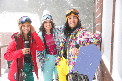 Photo of Friends with skis and snowboards wearing winter sport clothes outdoors