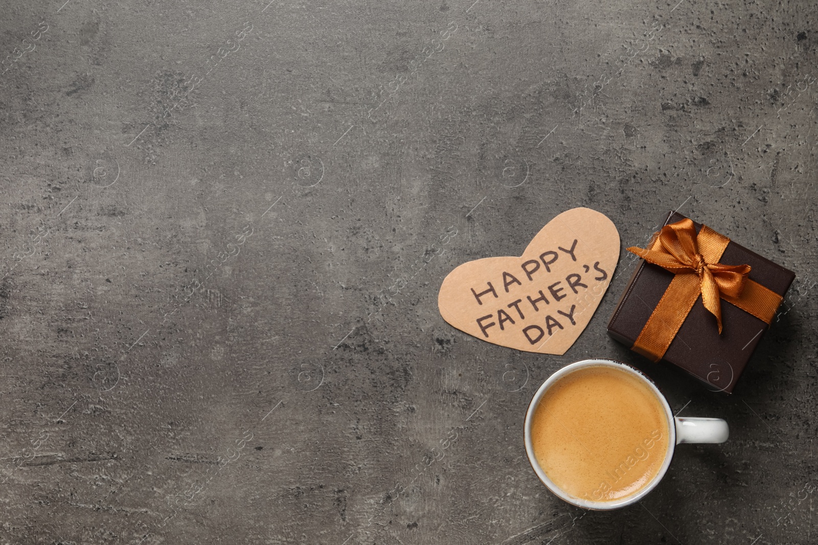 Photo of Heart shaped card with phrase HAPPY FATHER'S DAY, gift box and cup of aromatic coffee on grey background, flat lay. Space for text