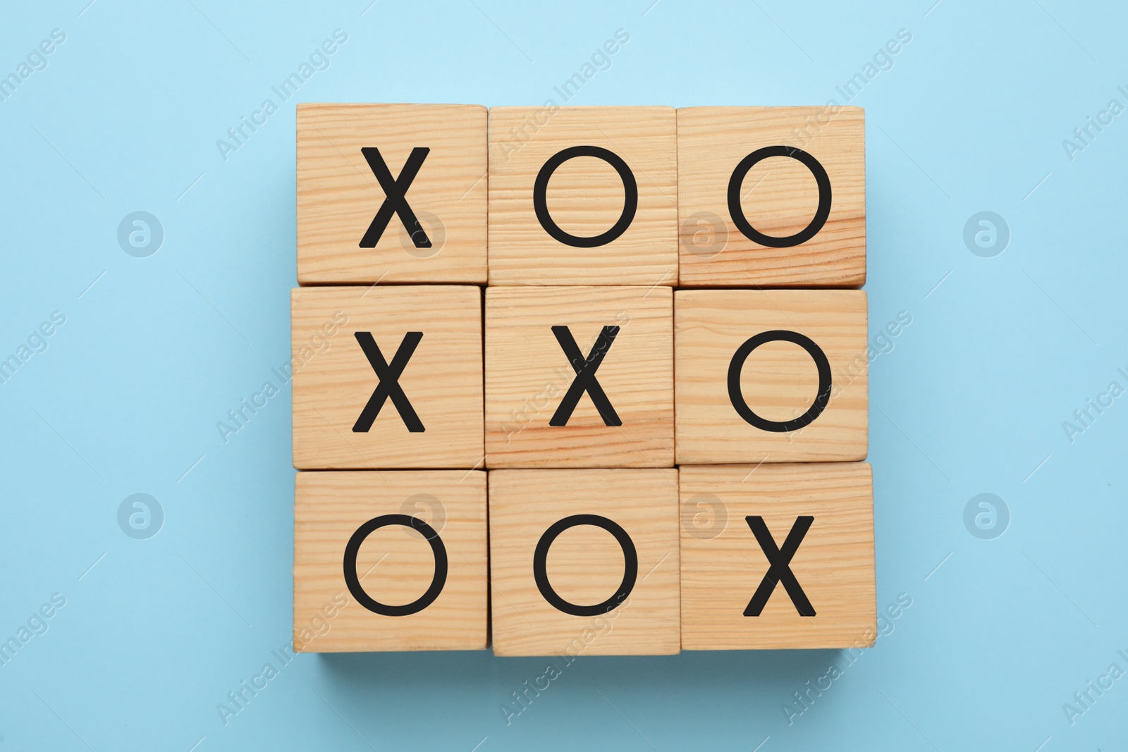 Photo of Tic tac toe cube set on light blue background, flat lay