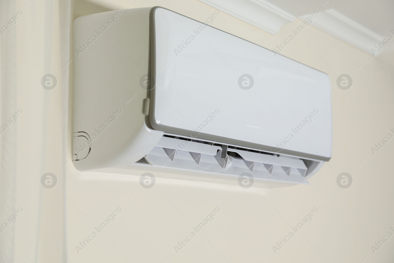 Photo of Modern air conditioner on white wall indoors