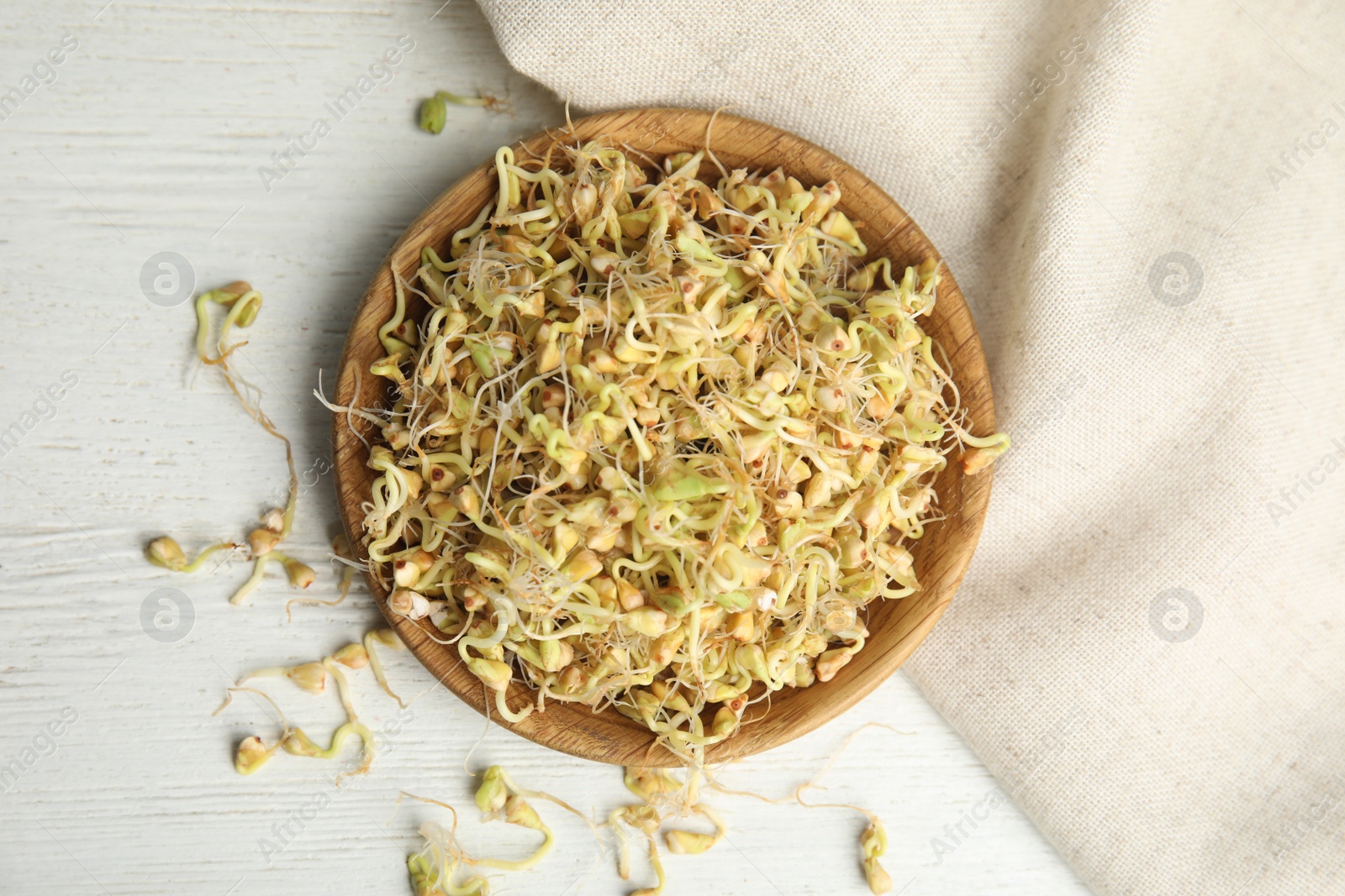 Photo of Plate with sprouted green buckwheat on white wooden table, flat lay