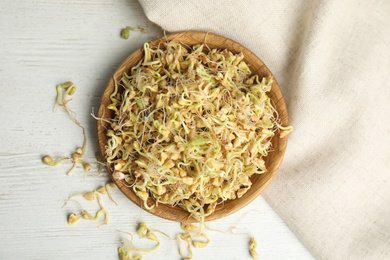 Plate with sprouted green buckwheat on white wooden table, flat lay