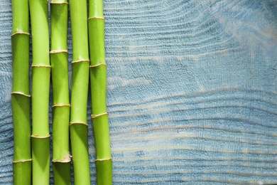 Green bamboo stems and space for text on wooden background, top view