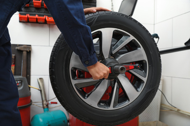 Photo of Man working with wheel balancing machine at tire service, closeup