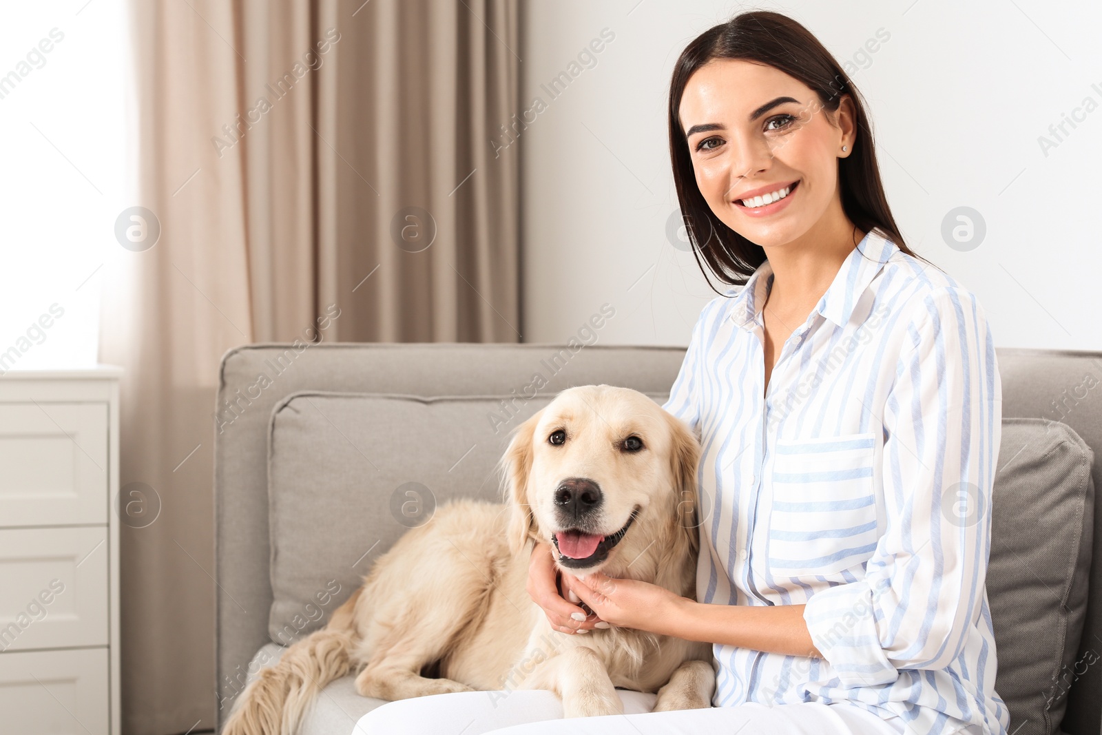 Photo of Young woman and her Golden Retriever dog in living room