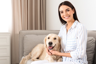 Photo of Young woman and her Golden Retriever dog in living room