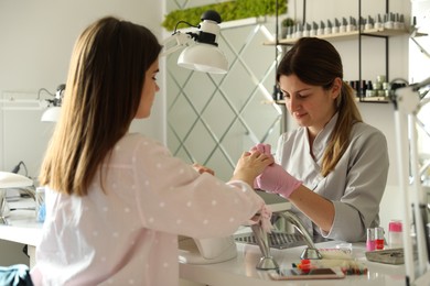 Photo of Professional manicurist working with client in beauty salon