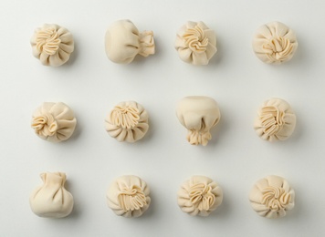 Photo of Composition with raw dumplings on white background, top view