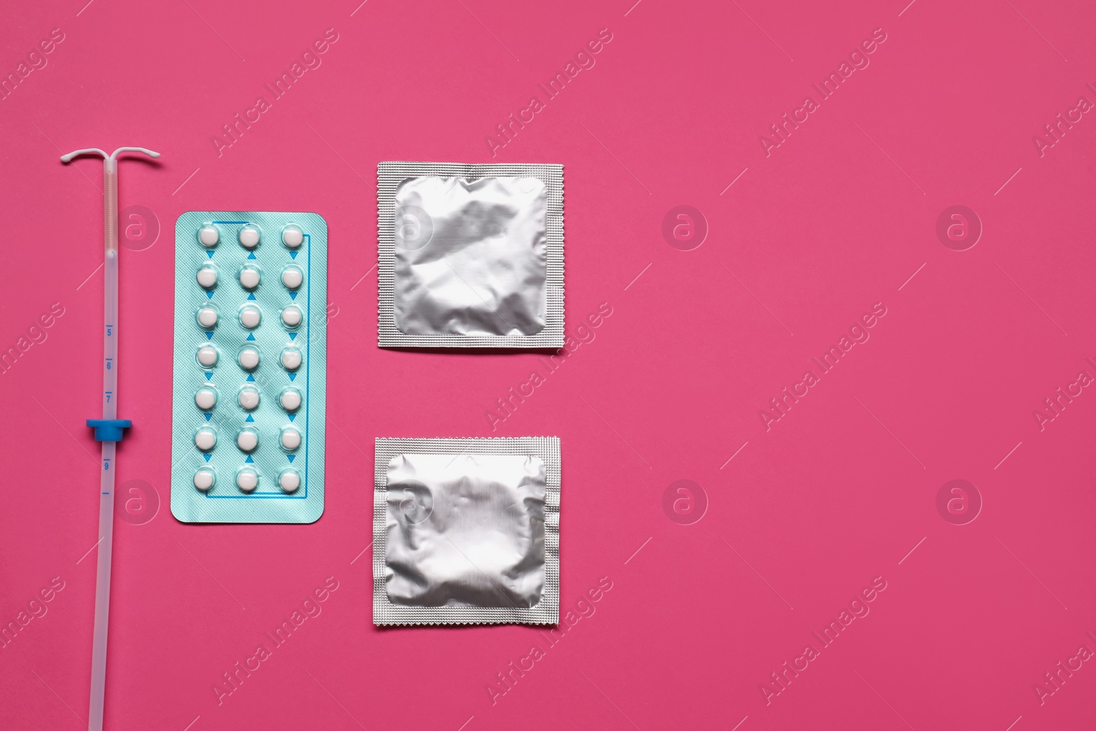 Photo of Contraception choice. Pills, condoms and intrauterine device on magenta background, flat lay. Space for text