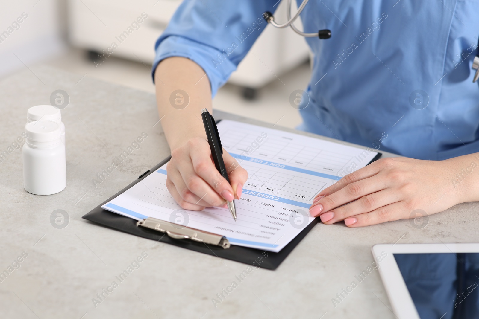 Photo of Doctor filling patient's medical card at table in clinic, closeup