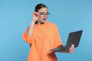 Photo of Beautiful woman in glasses with laptop on light blue background