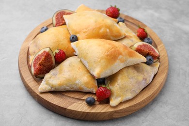 Photo of Delicious samosas with figs and berries on grey table, closeup