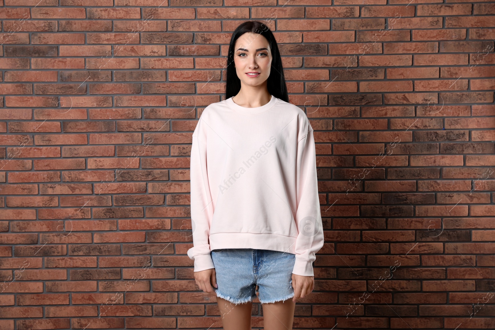 Photo of Portrait of young woman in sweater at brick wall. Mock up for design