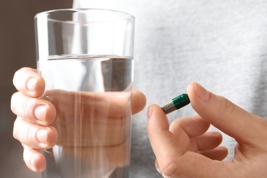 Photo of Woman holding spirulina pill and glass of water, closeup