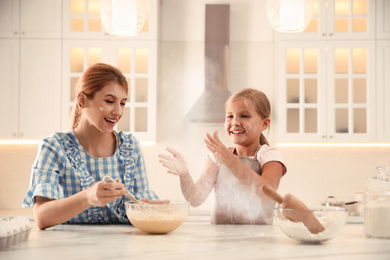 Photo of Mother and daughter making dough together in kitchen