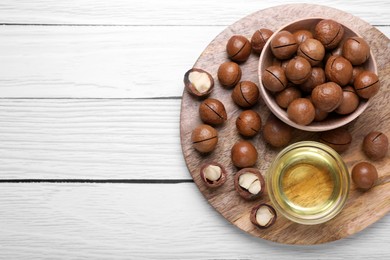 Photo of Delicious organic Macadamia nuts and natural oil on white wooden table, top view. Space for text