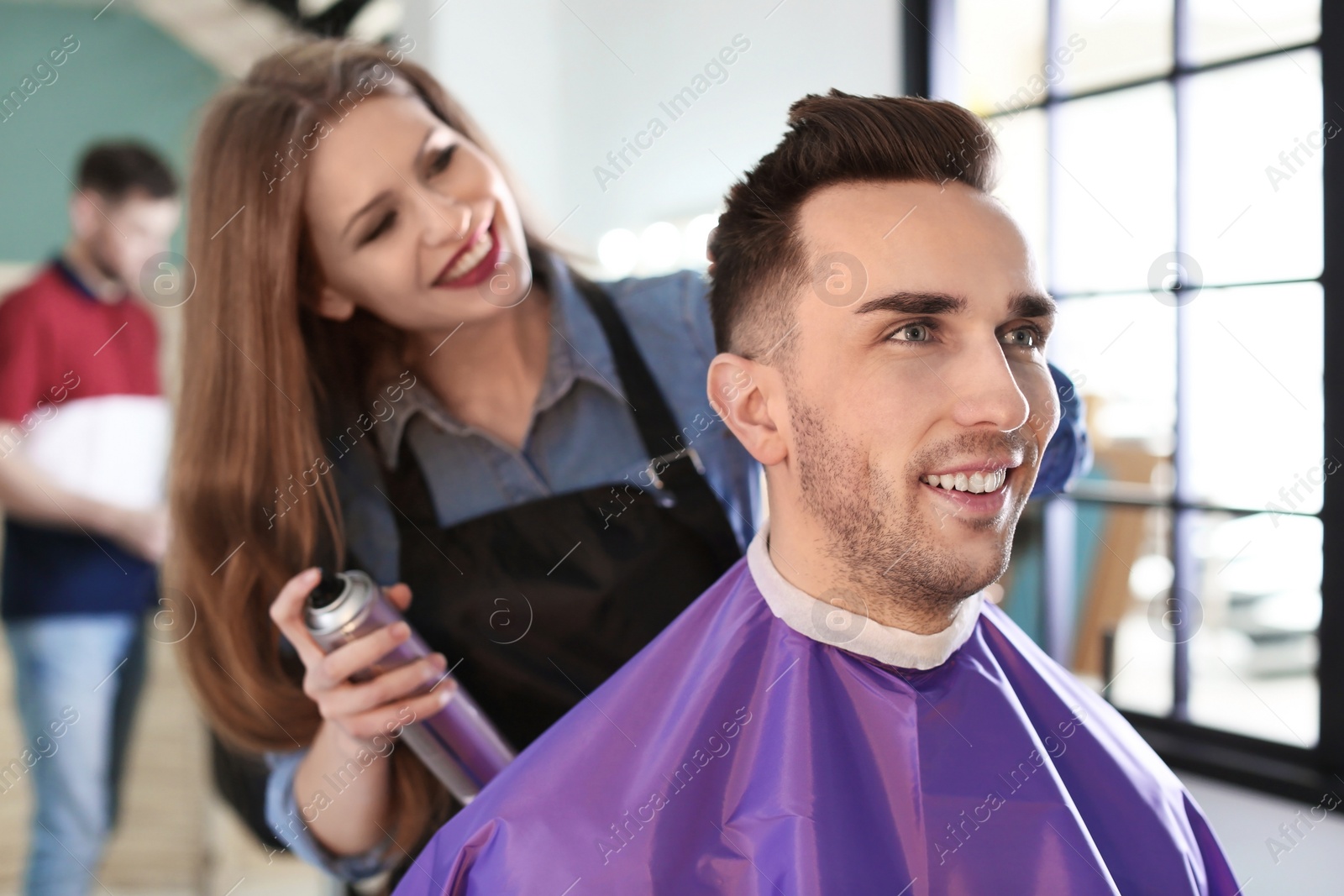 Photo of Professional hairdresser working with client in beauty salon