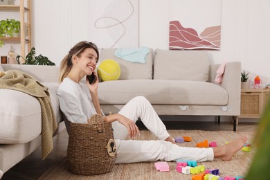 Photo of Young mother talking on phone in messy living room