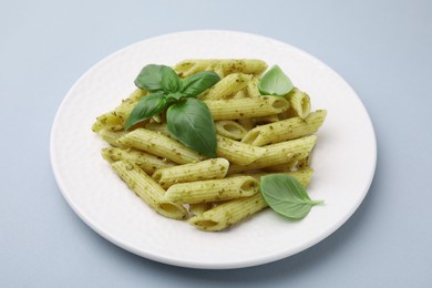 Photo of Delicious pasta with pesto sauce and basil on light grey background, closeup