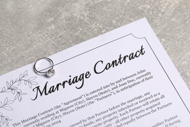 Photo of Marriage contract and ring with gemstone on grey table