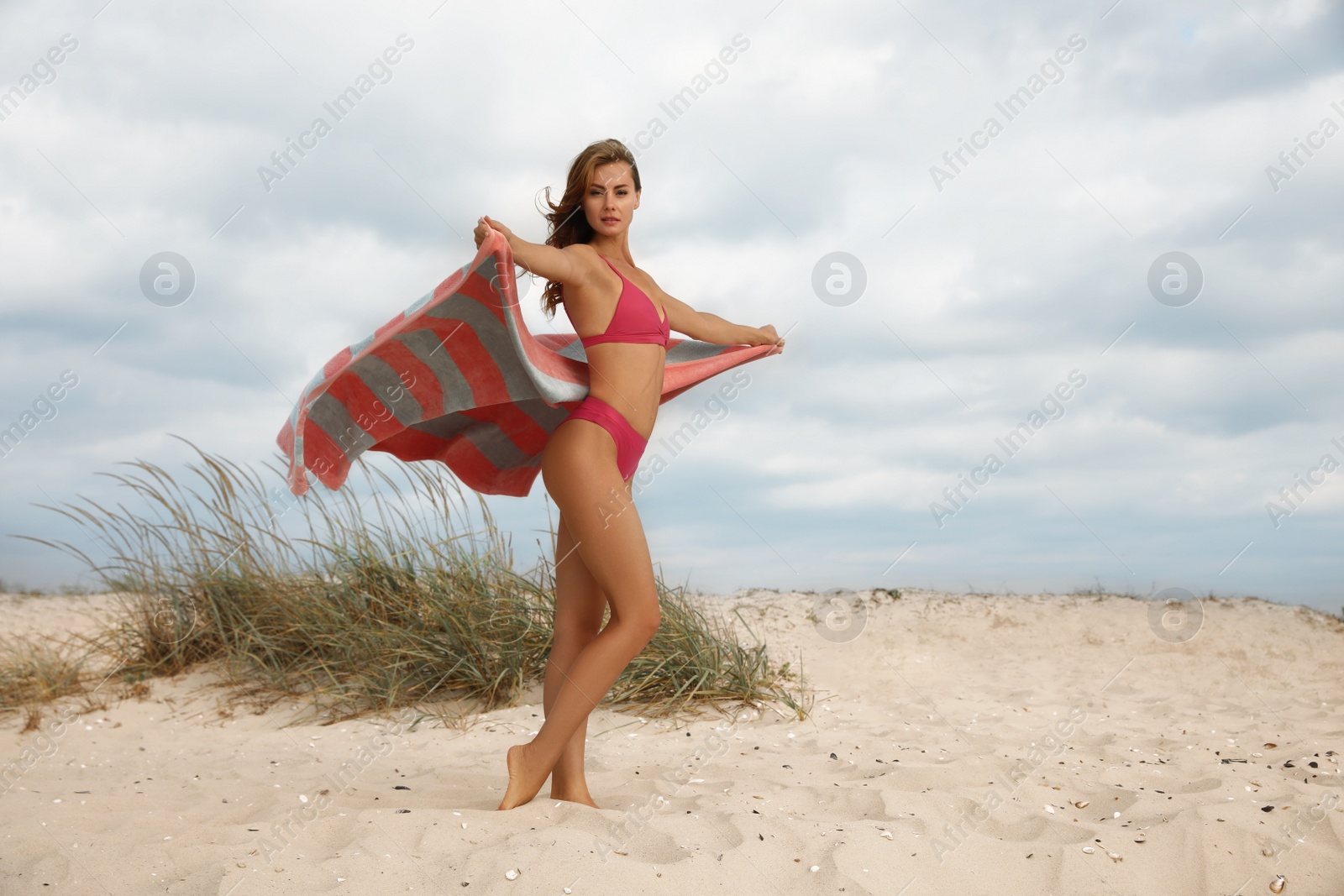 Photo of Beautiful woman in bikini with beach towel on sand