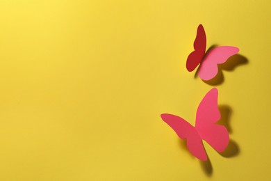 Bright pink paper butterflies on yellow background