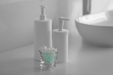 Photo of Glass holder with cotton buds on white countertop
