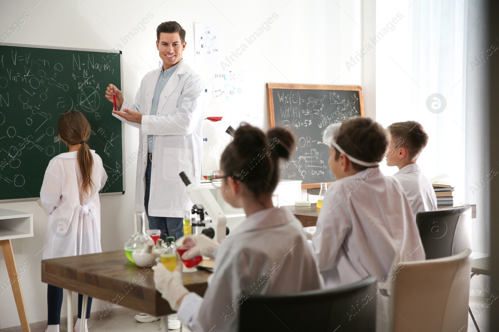 Photo of Teacher with pupils at chemistry lesson in classroom