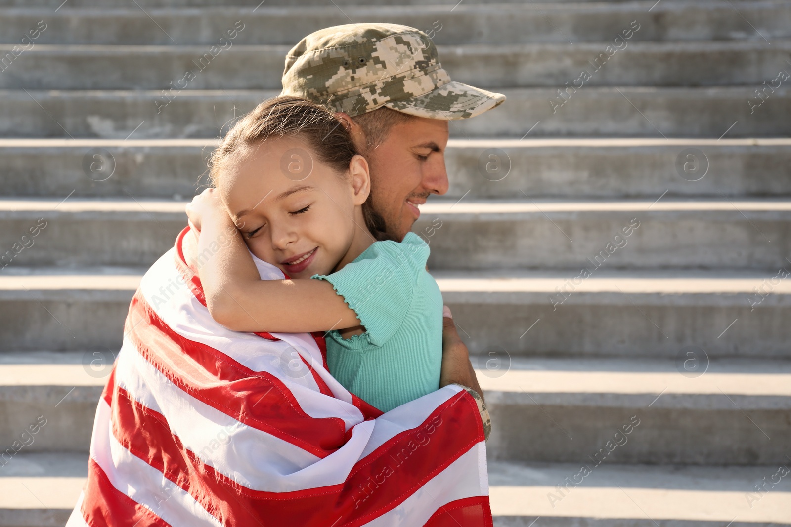 Photo of Soldier with flag of USA and his little daughter hugging outdoors, space for text