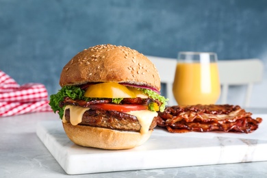 Photo of Fresh juicy bacon burger on marble table
