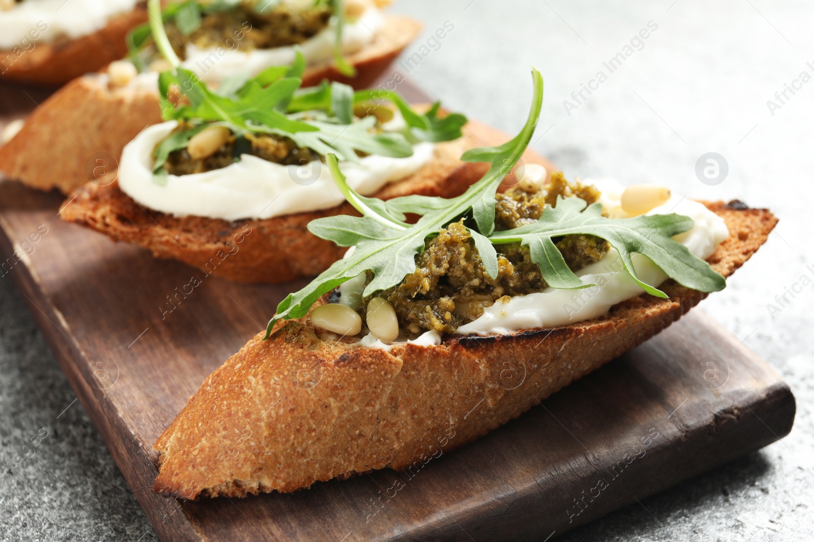 Photo of Serving board with tasty bruschettas on grey table, closeup