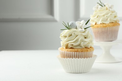 Tasty Easter cupcakes with vanilla cream on white table, space for text