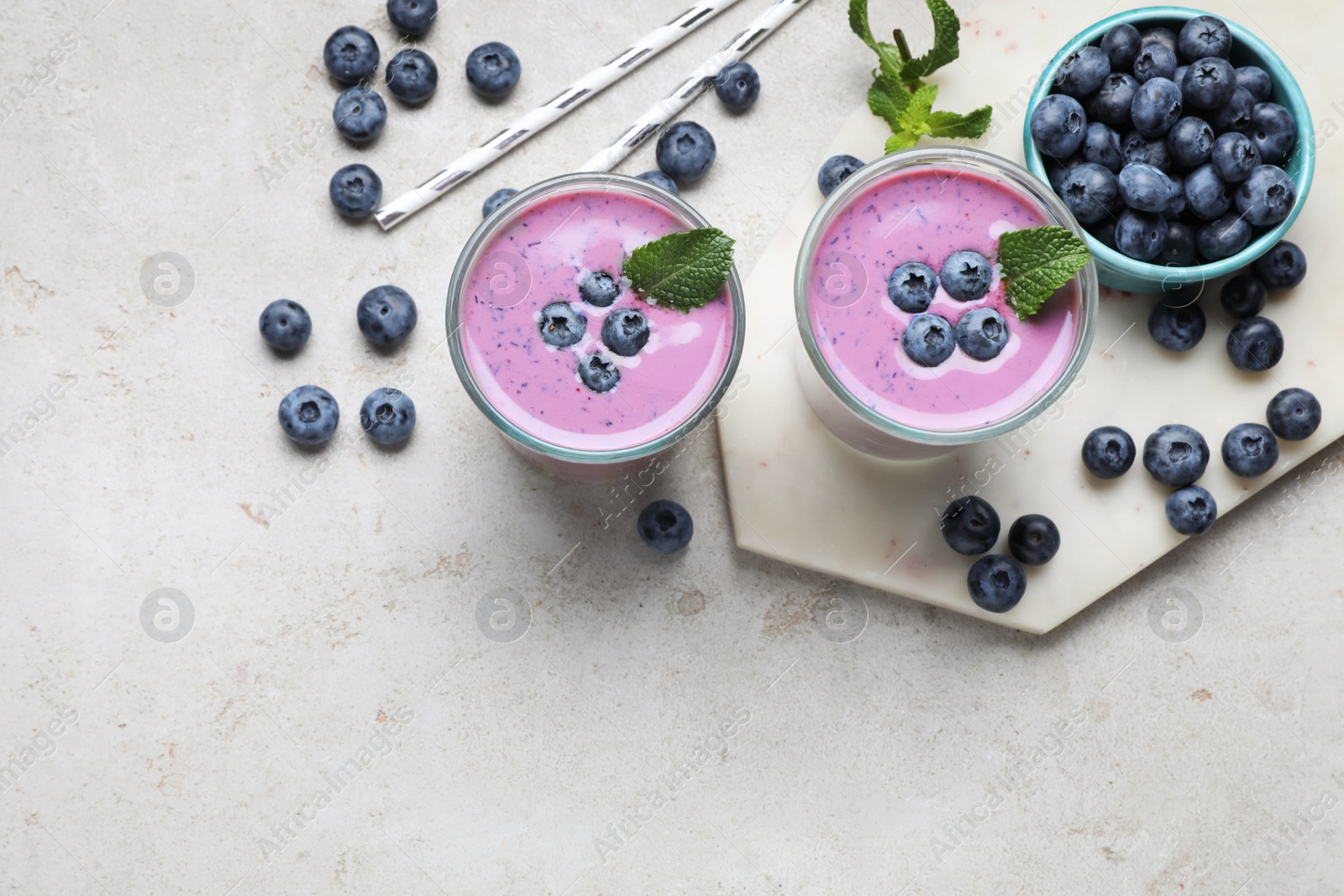 Photo of Freshly made blueberry smoothie on light grey table, flat lay. Space for text