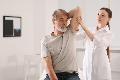 Professional orthopedist examining patient's shoulder in clinic