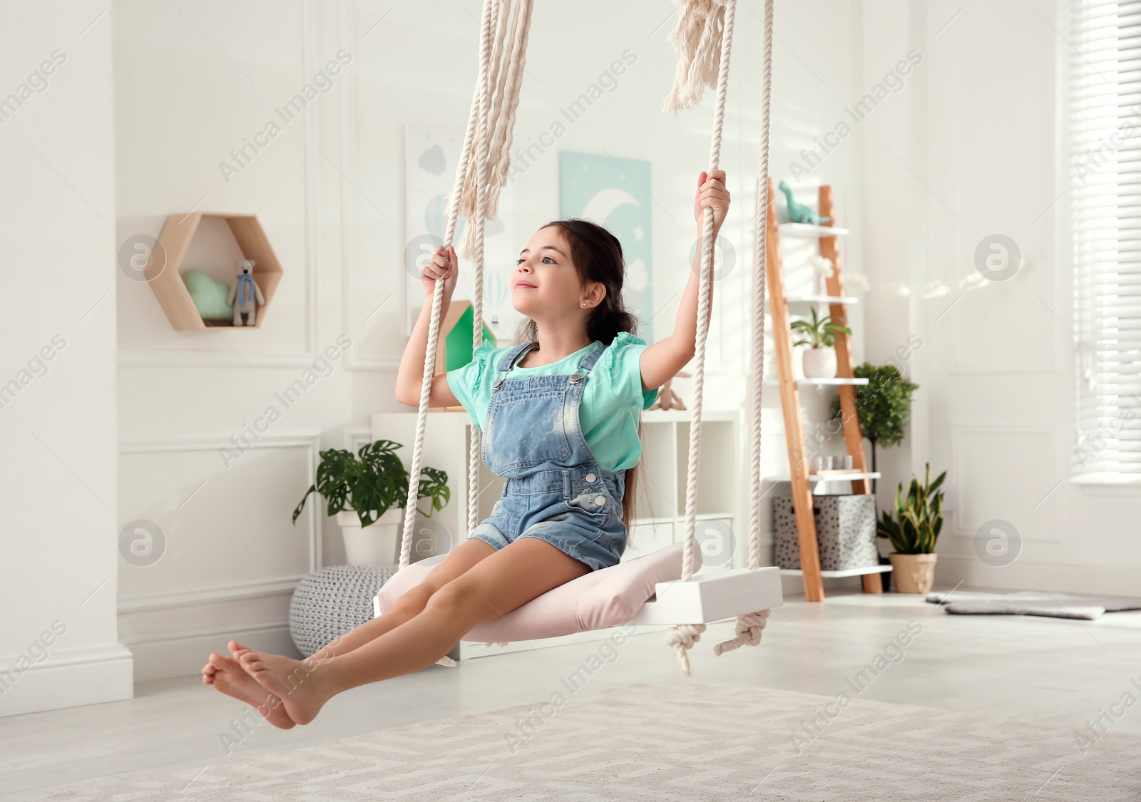 Photo of Cute little girl playing on swing at home