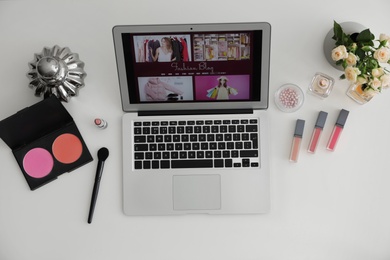 Photo of Laptop with open fashion blogger site on light background, top view
