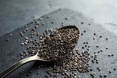 Photo of Spoon and scattered chia seeds on slate plate, closeup