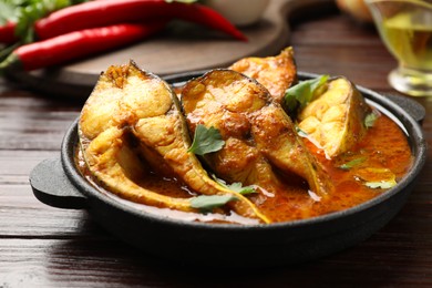 Photo of Tasty fish curry on wooden table, closeup. Indian cuisine