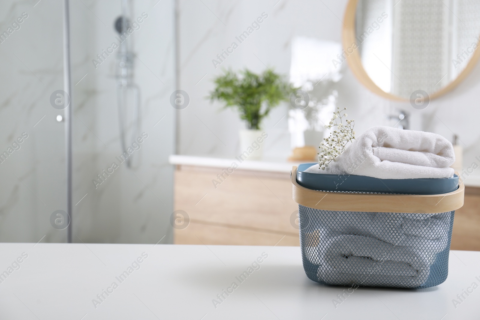 Photo of Basket with clean soft towels in bathroom. Space for text