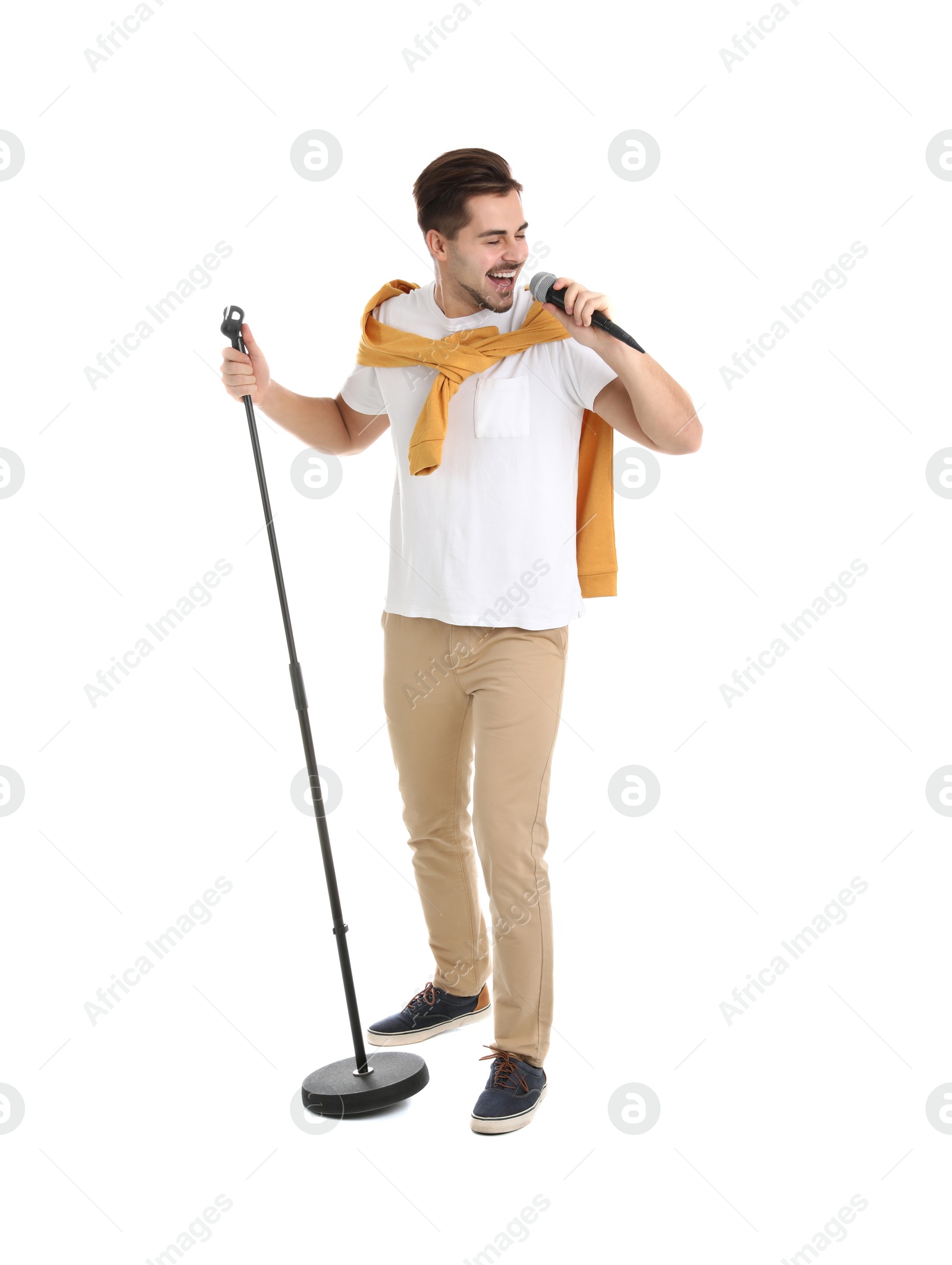 Photo of Young handsome man in casual clothes singing with microphone on white background