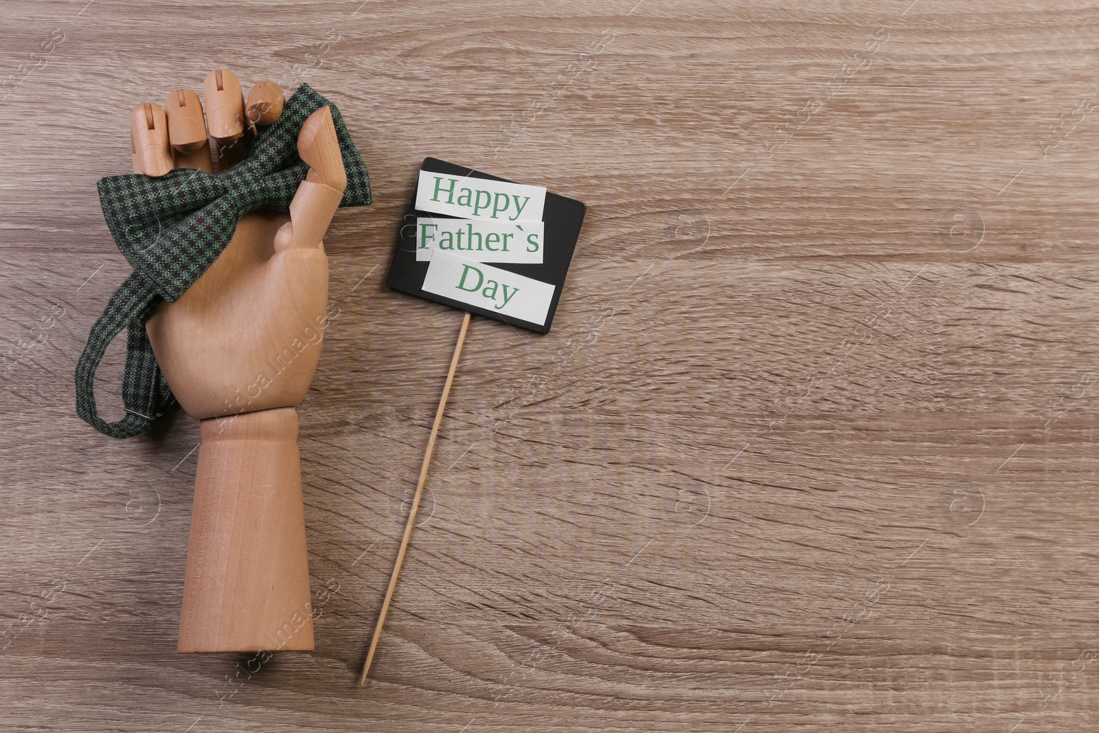 Photo of Hand holding bow tie on wooden background. Father's day celebration