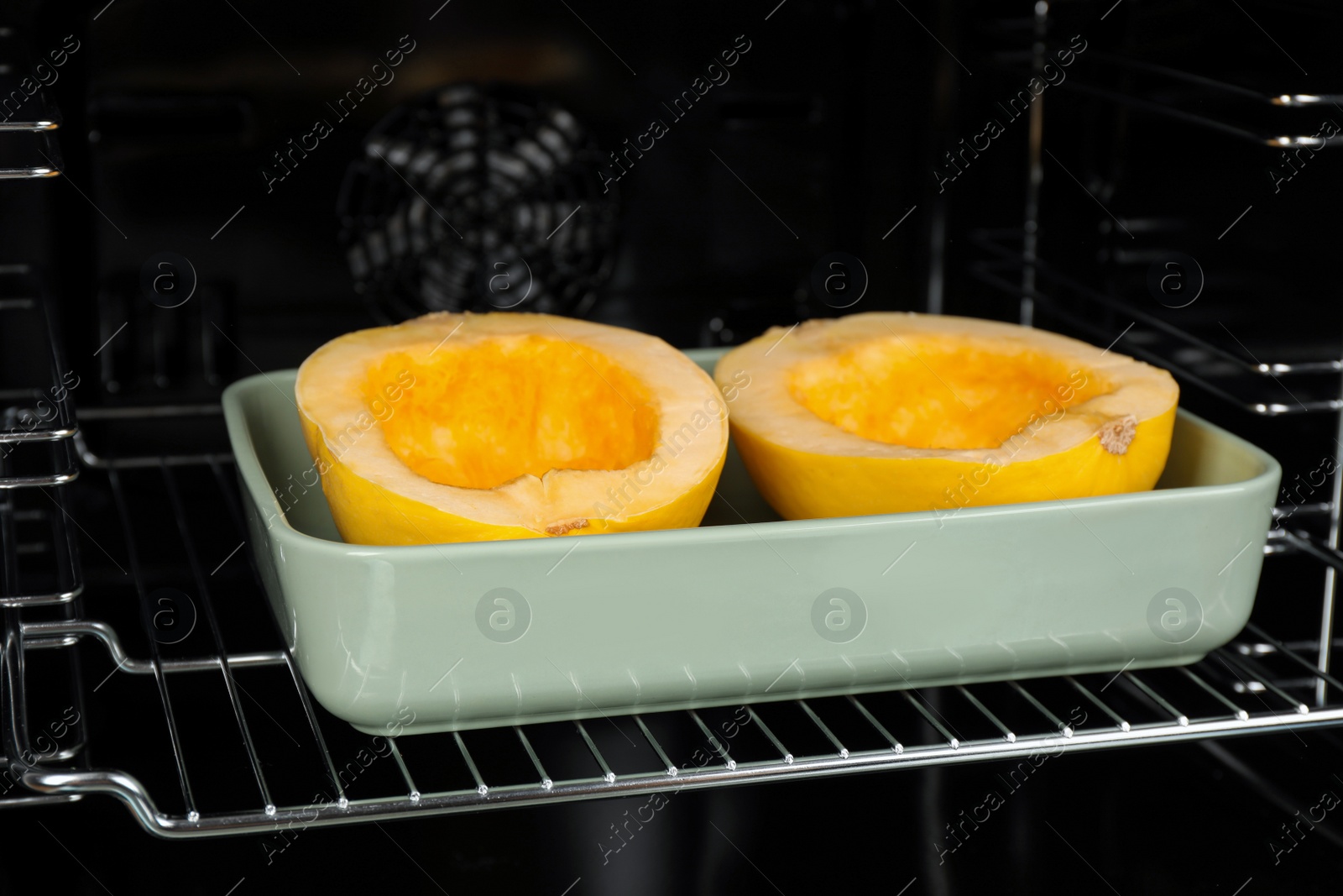 Photo of Baking dish with halves of fresh spaghetti squash in oven