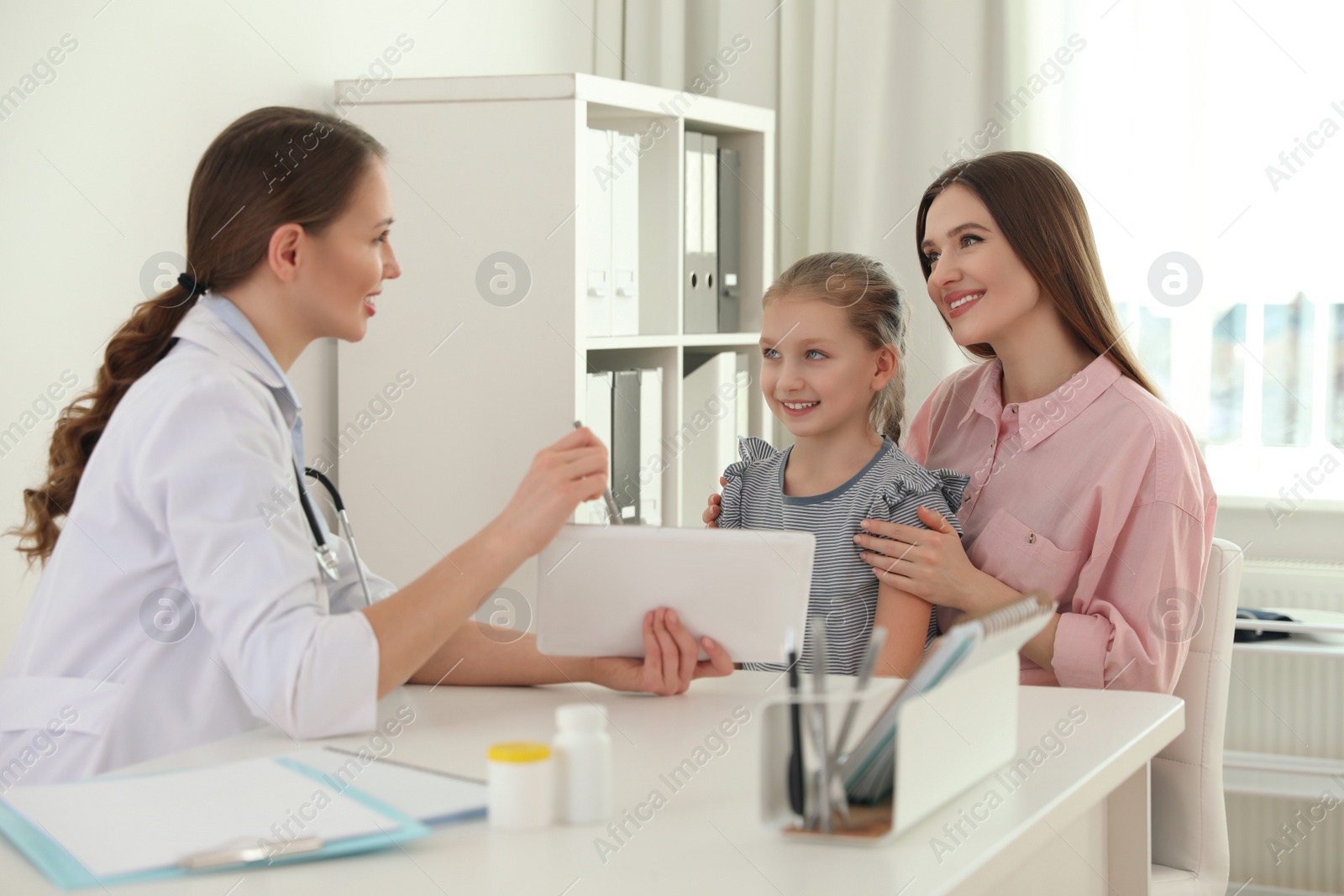 Photo of Mother and daughter visiting pediatrician. Doctor working with patient in hospital