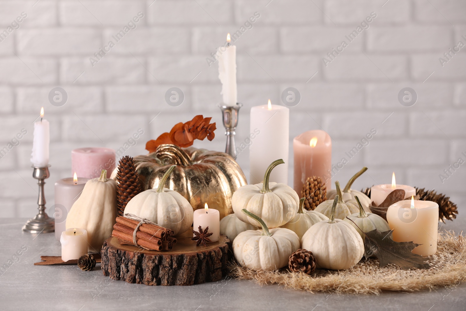 Photo of Beautiful composition with pumpkins and burning candles on table