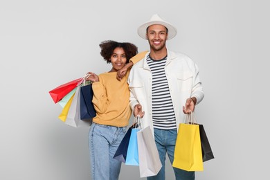 Photo of Happy African American couple with shopping bags on light grey background