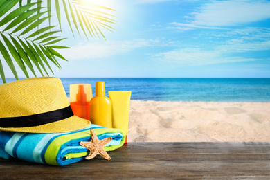 Beach objects on wooden table near sea, space for text. Summer vacation 