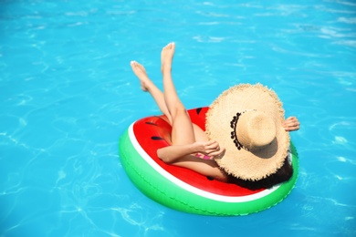 Photo of Young woman with inflatable ring in blue swimming pool