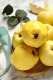 Photo of Fresh ripe organic quinces with leaves on white marble table