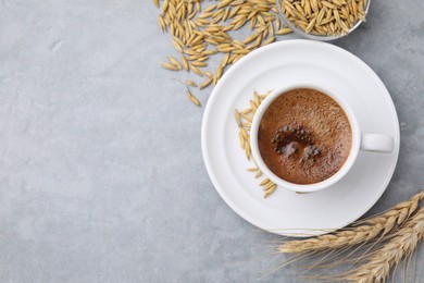 Photo of Cup of barley coffee, grains and spikes on gray table, flat lay. Space for text
