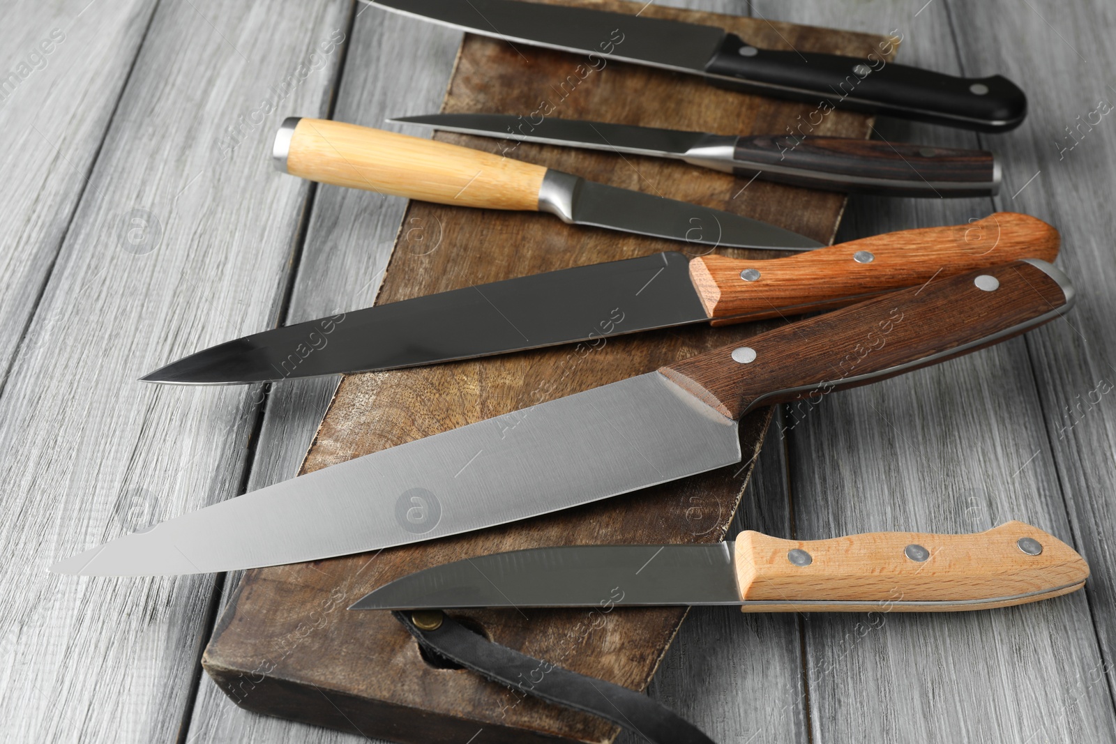 Photo of Many different knives and board on light wooden table